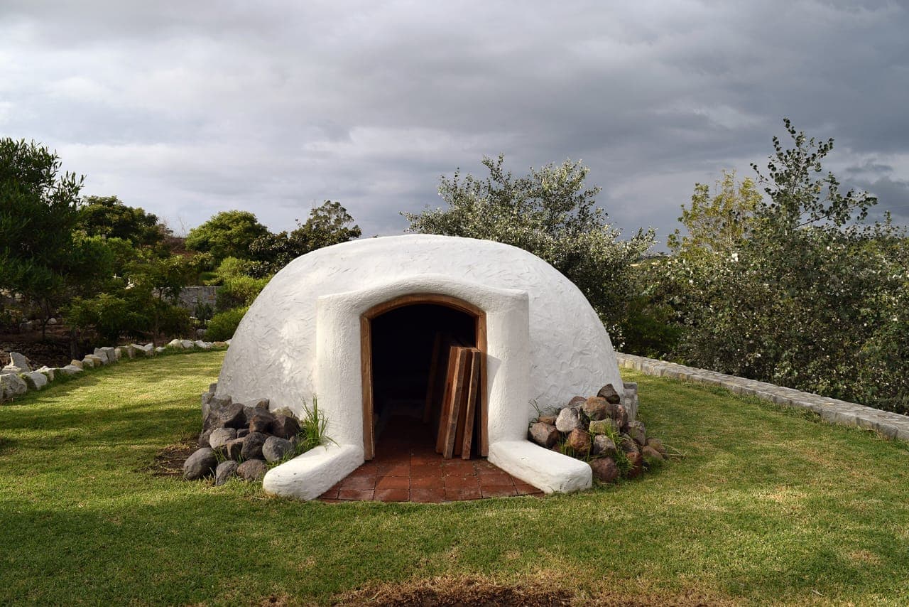The temazcal, white-domed sweat lodge under cloudy Andean sky