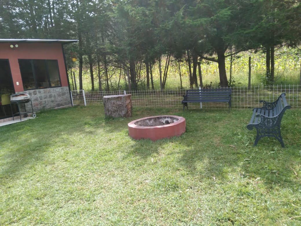 Fire pit, benches, and the small kitchen cabin in the gathering area at Calacalí