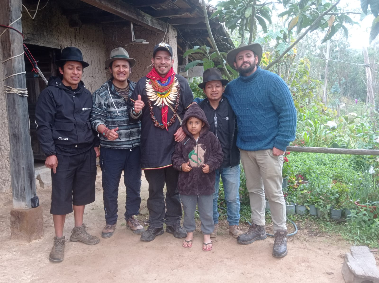 Gabriel with Taitas of the Cofán community in front of a traditional adobe dwelling