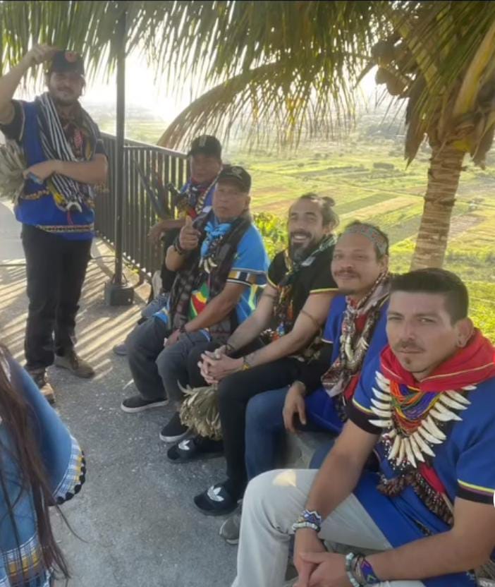 Gabriel with fellow medicine carriers gathered under a palm canopy